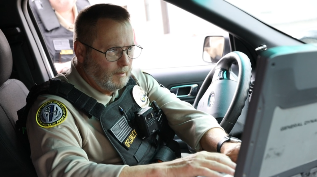 A private security officer working on a laptop