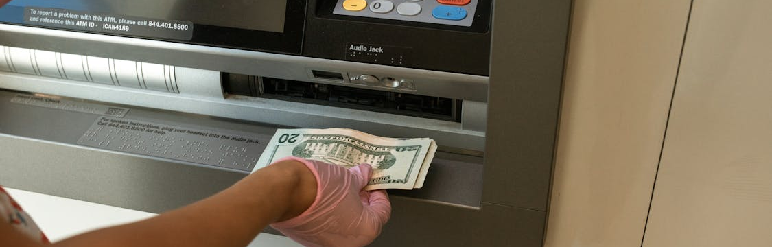 A person taking out money from an ATM using a credit card