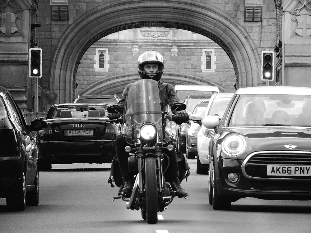 A security professional riding a motorcycle through traffic