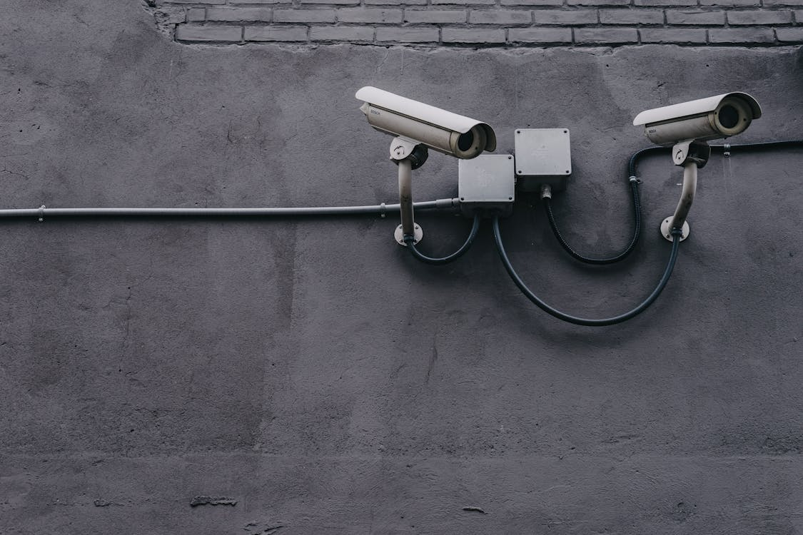 Two gray bullet security cameras on a wall