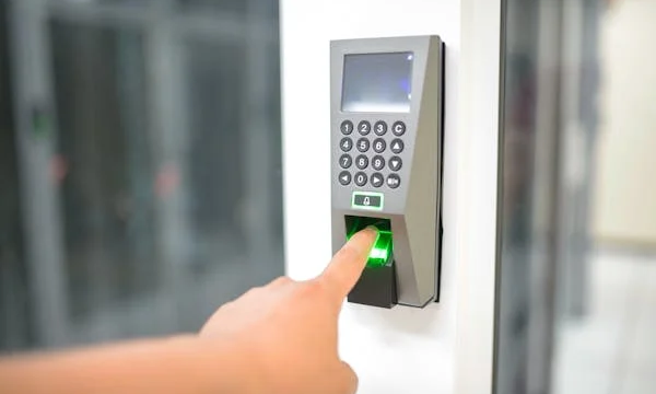 A man scanning his fingerprint on a biometric scanner to gain access to a secure office area.