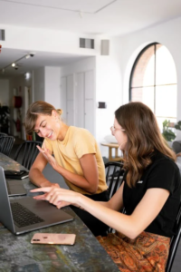 An image of two smiling women looking at a laptop 