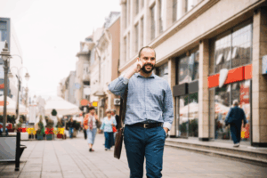 Smiling man walking with a phone in a busy shopping area