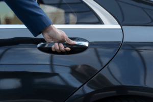 Close-up of a hand opening the door of a dark security vehicle